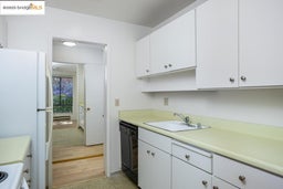 Kitchen with freestanding refrigerator, light countertops, black dishwasher, and white cabinets