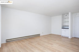 Unfurnished living room featuring baseboard heating and light wood-type flooring