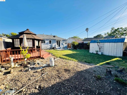 Backyard featuring a covered gazebo on a wood deck, a storage shed, and a grassy lawn area