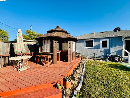 Expansive wood-finish deck featuring a built-in gazebo with a shingled roof, integrated bar seating, and privacy panels