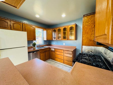 Kitchen featuring wood-finish cabinetry, a gas range, a double basin sink, and a dishwasher