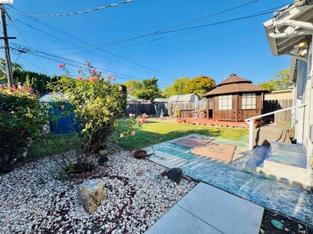 Expansive backyard featuring a central lawn, decorative stone landscaping, and a wooden gazebo with a multi-tiered roof