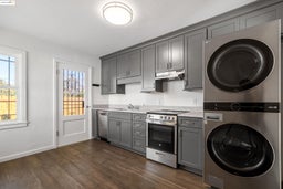 Laundry area featuring dark wood finished floors and stacked washer / dryer