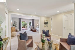 Living area with light colored carpet, ornamental molding, and recessed lighting