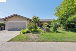 Ranch-style house with driveway, a garage, and a front lawn