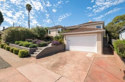 View of front of home featuring stucco siding, a chimney, a tiled roof, and driveway