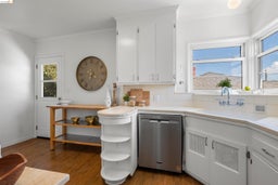 Kitchen featuring white cabinets, backsplash, stainless steel dishwasher, dark wood-style flooring, and crown molding