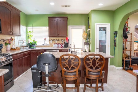 Kitchen featuring wood cabinetry, light-colored countertops, stainless steel appliances, and a mosaic tile backsplash
