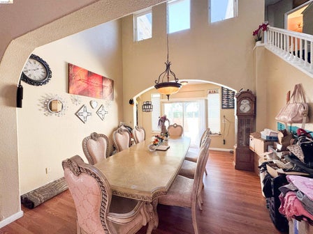 Dining area featuring high ceilings, wood-finish flooring, and an arched doorway