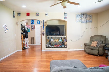 Spacious interior featuring wood-finish flooring, light-colored walls, and a ceiling fan with integrated lighting
