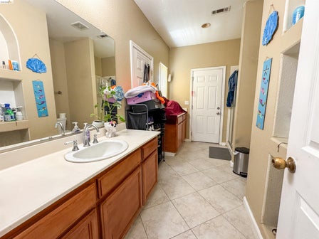Vanity featuring an integrated sink, cream-colored countertop, and wood-finish cabinetry