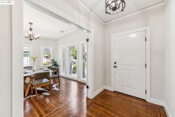 Entryway with a chandelier, dark wood-type flooring, and crown molding