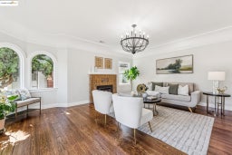 Living area featuring dark wood-style floors, a fireplace, a chandelier, and crown molding