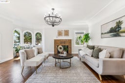 Living room with wood finished floors, a chandelier, a tile fireplace, and crown molding