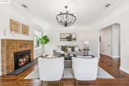 Living area featuring arched walkways, dark wood-style flooring, and a glass covered fireplace