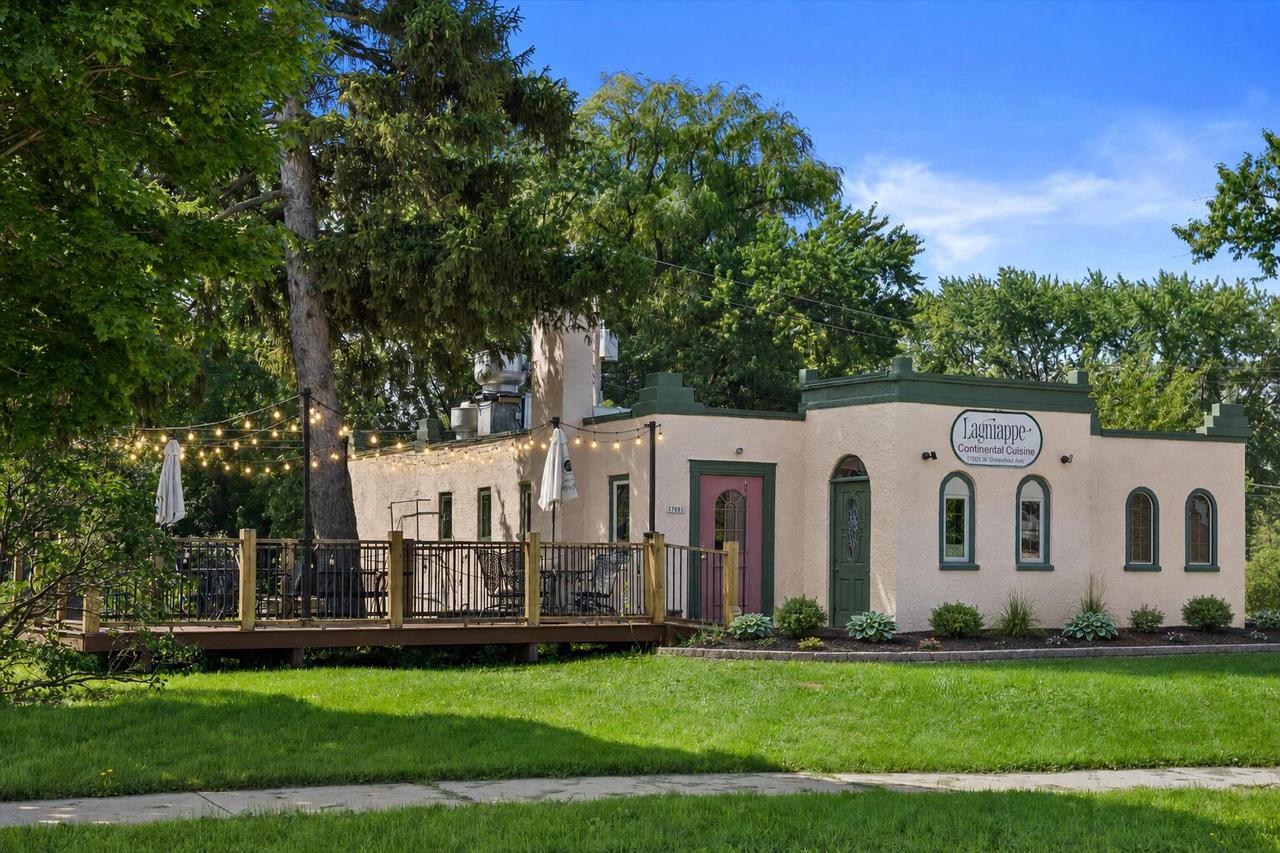 Lagniappe Continental Cuisine, a cream-colored restaurant with green trim and a tree-shaded outdoor deck.