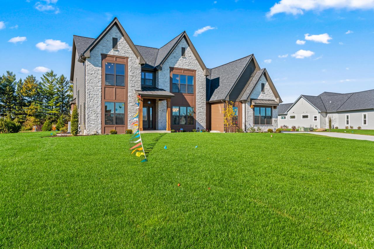 Two-story stone-and-siding home with multiple gables and a broad green lawn.