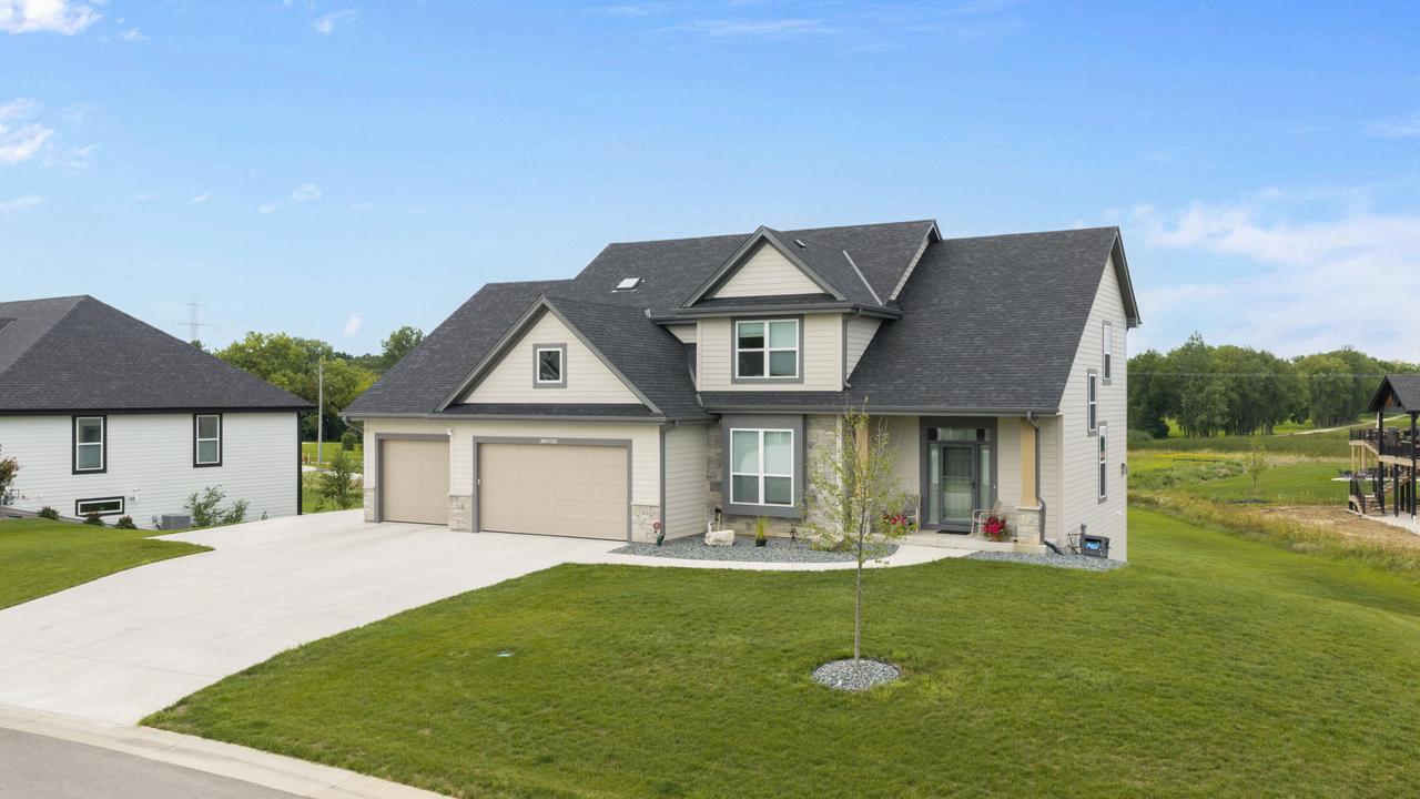 Two-story home with a broad driveway, attached garage, and landscaped front lawn.