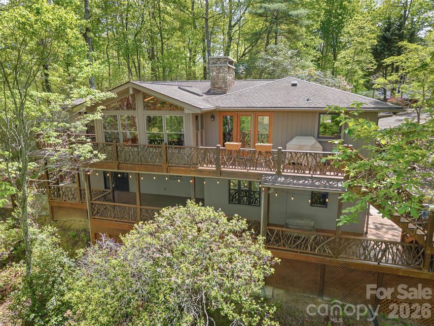 This mountain home offers the rare combination of long distance Blue Ridge Parkway views, lake access, and exceptional privacy on a private wooded double lot in Connestee Falls. Extensively remodeled in 2012, the home blends classic mountain character with thoughtful updates and is ideally located near the clubhouse and community amenities. A maintained trail from the property leads to Lake Tiaroga, where residents enjoy swimming, fishing, and use of the community dock.
The double lot setting provides additional space and privacy, creating a peaceful mountain retreat surrounded by natural beauty.
The main level features an open living area with fireplace, expansive windows, and direct access to a large deck with grilling area and stunning views. The primary bedroom and an additional bedroom are located on the main level, providing flexible one level living options.
The lower level includes two additional bedrooms, a spacious family room with a second fireplace, a wet bar, and a built in office area designed for two, ideal for remote work, hobbies, or study space. A covered porch offers a generous sitting area with space for a hot tub while overlooking the private wooded surroundings.
An oversized one car garage provides excellent storage and functionality, while extensive custom stone hardscaping connects the upper and lower outdoor spaces and enhances the natural mountain setting.
This property truly captures the best of Connestee Falls living with long distance mountain views, lake access, privacy, and close proximity to community amenities.