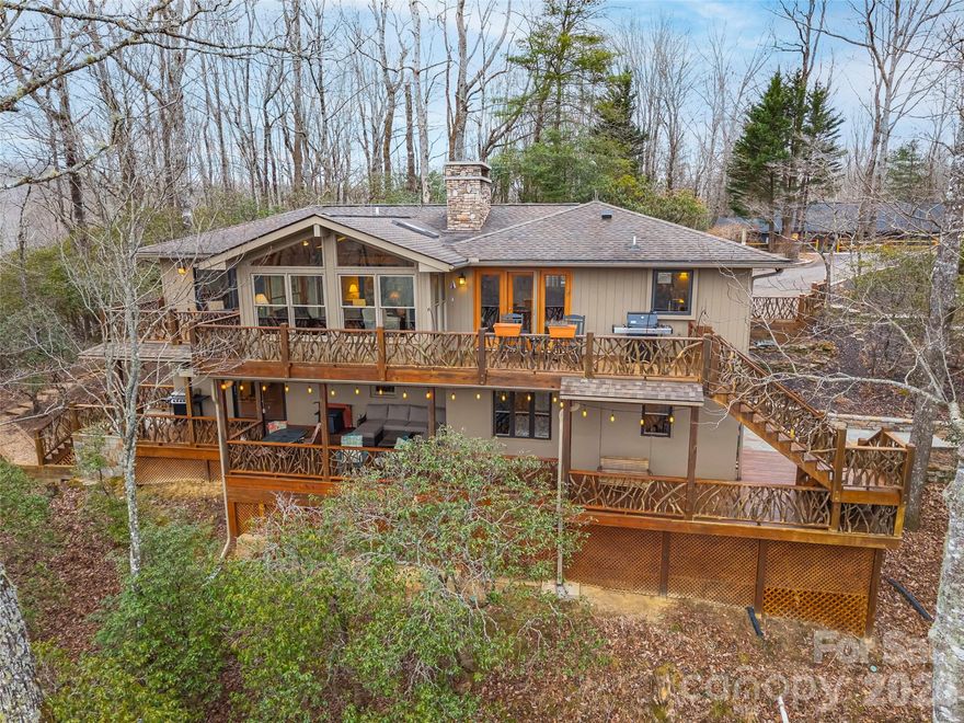 This mountain home offers the rare combination of long distance Blue Ridge Parkway views, lake access, and exceptional privacy on a private wooded double lot in Connestee Falls. Extensively remodeled in 2012, the home blends classic mountain character with thoughtful updates and is ideally located near the clubhouse and community amenities. A maintained trail from the property leads to Lake Tiaroga, where residents enjoy swimming, fishing, and use of the community dock.
The double lot setting provides additional space and privacy, creating a peaceful mountain retreat surrounded by natural beauty.
The main level features an open living area with fireplace, expansive windows, and direct access to a large deck with grilling area and stunning views. The primary bedroom and an additional bedroom are located on the main level, providing flexible one level living options.
The lower level includes two additional bedrooms, a spacious family room with a second fireplace, a wet bar, and a built in office area designed for two, ideal for remote work, hobbies, or study space. A covered porch offers a generous sitting area with space for a hot tub while overlooking the private wooded surroundings.
An oversized one car garage provides excellent storage and functionality, while extensive custom stone hardscaping connects the upper and lower outdoor spaces and enhances the natural mountain setting.
This property truly captures the best of Connestee Falls living with long distance mountain views, lake access, privacy, and close proximity to community amenities.