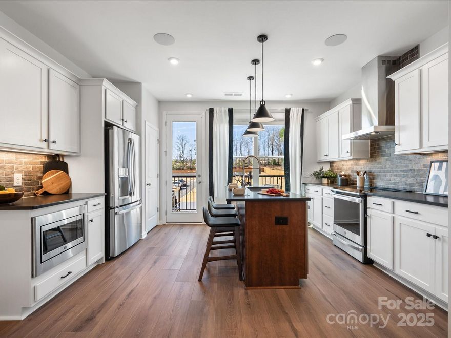 Final opportunity for The Collins, a striking townhome designed with the Bobby Berk Tailored Industrial Collection. This move-in-ready home blends modern sophistication with bold, timeless style, featuring black quartz countertops, crisp cream cabinetry, matte black hardware, and rich warm-toned flooring that create a cohesive, designer-curated aesthetic. The gourmet kitchen balances style and function, flowing seamlessly into connected living spaces with 9-foot ceilings across three bright, airy floors. The grand primary retreat is flooded with natural light and includes a walk-in shower and a generous walk-in closet. Sliding doors from the kitchen open to an outdoor living space, perfect for entertaining or relaxing. With included appliances and blinds, every detail has been thoughtfully considered to elevate everyday living in a home that is as functional as it is striking.