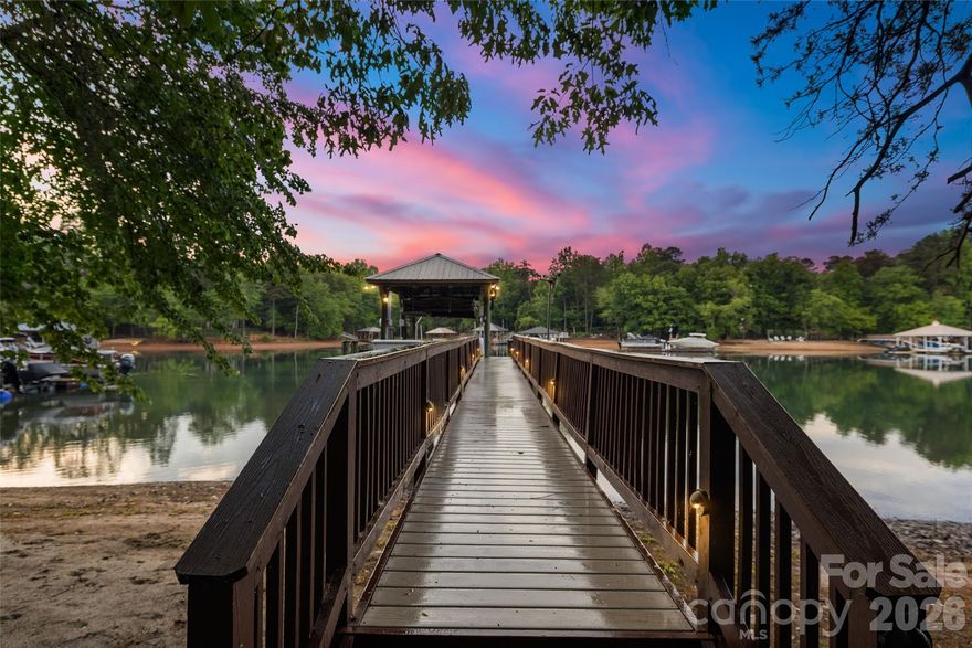 Experience elevated lakefront living in Denver’s premier Sailview community! Situated on an exclusive lot with 76 feet of private shoreline, this exceptional waterfront property features a deep-water pier designed for both convenience and entertainment. The composite-decked dock includes a fixed pier, boat lift, WiFi access, Sonos sound system, motorized automatic touchless boat cover with remote, and remote-powered jet ski lift, everything you need for effortless days on the water. Enjoy your own private sandy beach and firepit, the perfect setting for sunset gatherings by the water.The backyard is a true entertainer’s retreat with a stunning two-level terrace highlighted by a new patio (2019), composite decking, and a dramatic double-sided stone fireplace. Relax year-round in the Bull Frog A9 spa, enjoy two gas heaters for cooler evenings, and take advantage of the outdoor shower after lake days. Additional exterior features include in-ground irrigation pumped directly from the lake, a 10x10 storage shed, landscape lighting, and a tranquil water fountain. Inside, a soaring 19-foot foyer ceiling makes an unforgettable first impression, with 12-foot ceilings throughout the dining and living rooms enhancing the open, airy feel. Hardwood floors were refinished in 2019 with a rich walnut stain. The kitchen showcases painted cabinetry and island, granite countertops, KitchenAid appliances, and a sunny breakfast nook framed by a wall of windows overlooking the lake. The great room features a gas log fireplace with custom built-ins, while a beautifully appointed sunroom (completed in 2019) offers a floor-to-ceiling stone fireplace topped with a reclaimed wood mantel. The main level also includes a secondary bedroom with full bath and a spacious laundry room with cabinetry and ample storage. Upstairs, the primary suite provides a private retreat alongside two additional bedrooms and an expansive bonus room with built-in desks, custom bench seating, and durable vinyl plank flooring. The finished basement expands the living space with an office or fifth bedroom, full bath, kitchenette, sitting room, recreation area with included pool table, media room, and abundant storage. Residents of Sailview enjoy access to a community pool, pickleball and tennis courts, clubhouse, and year-round social event, offering not just a home, but a lifestyle.