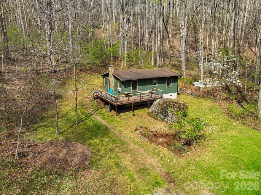 A unique opportunity to own 51.05 acres of pure tranquility. Tucked deep into nature with no road noise, this private retreat features a charming 2-bedroom, 2-bath cabin offering 768 sq ft of simple, intentional living. The vintage Fisher woodstove creates the ultimate cozy feel. The large deck invites you to take in seasonal views of Craggy Pinnacle. Natural spring water runs through the property, enhancing the peaceful, storybook setting. With Open Use Zoning and multiple additional build sites on the property, the possibilities are endless. Create a multi-dwelling compound, private getaway, or legacy estate. The resilient Big Ivy Community is brimming with outdoor recreation opportunities. This is mountain living at its most serene. Rare, raw, and remarkably peaceful.