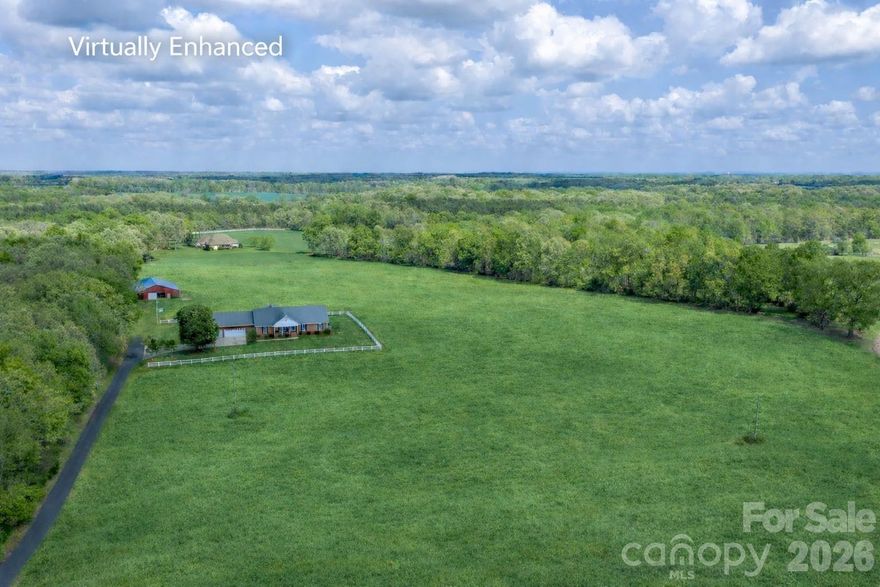 The Williams Family Farm
A versatile 25+ acre property offering a gentleman’s farm, hobby farm, equestrian estate, or multi-generational living opportunity. Thoughtfully maintained by its original owners, the land features a balanced mix of open fields and mature hardwoods—ideal for farming, recreation, or future expansion.

Fields are currently planted in crops and can be easily converted to pasture for horses or livestock. The wooded acreage provides space for trails, hunting, or potential additional homesites.

The main barn offers multiple functional spaces including garage, workshop, equipment storage, run-in/feed shelter, pull-through tractor shed, and a large hay storage area with potential for stall conversion. An additional run-in shelter provides further protection for animals.

The custom-built brick home is designed for comfortable one-level living, with a walk-up attic offering expansion potential. Enjoy peaceful pasture views, sunrises, and sunsets from both the front porch and the large covered back porch—ideal for entertaining or everyday living.

Inside, the home features a spacious layout with strong construction and well-maintained systems. The dining area opens to the great room, showcasing farm views through multiple windows and glass doors. Built-in bookshelves and cabinetry add character, while a corner propane fireplace anchors the space.

The kitchen includes custom ash cabinetry, an island, breakfast bar, wall pantry, and is open to the breakfast area with a wood-burning stove. Both the great room and breakfast area provide direct access to the covered back porch.

Additional highlights include abundant storage, a large laundry/mudroom with office potential, and a split-bedroom layout. The primary suite offers dual walk-in closets and a spacious bath with separate vanities and water closets. Secondary bedrooms share a full bath with dual vanity and tub/shower combination.

The three car garage has two storage rooms that can be used for a variety of purposes including, workshop, hobbies and canning.

Conveniently located between Marshville and Wingate with easy access to Monroe via Highway 74 or the Hwy 74 Expressway which offers a straightforward commute to Charlotte.