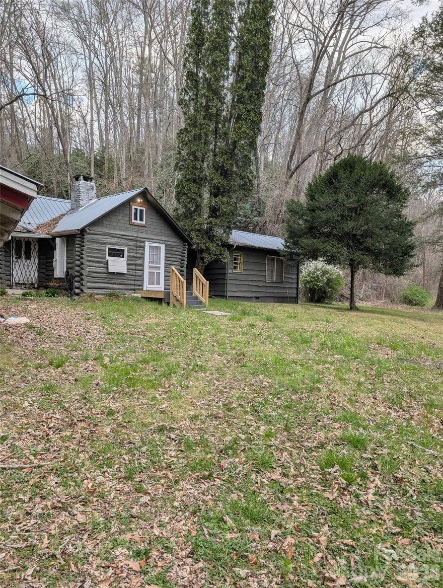 This charming, rustic log cabin offers a rare opportunity just 4 miles from downtown Blowing Rock. This 1 bedroom, one bathroom home with a loft space that can be used for sleeping quarters sits on nearly 7 acres of beautiful scenic mountain land featuring natural springs, and seasonal views. The kitchen has a working antique porcelain Hotpoint electric stove (valued at $4,500). With a few thoughtful updates, this property could serve as a unique investment, private mountain retreat, or vacation rental. The living area has a two-story great room, with an original stacked stone fireplace with working wood stove. Heat and air are also available from 2 mini split units in the living room and primary bedroom.