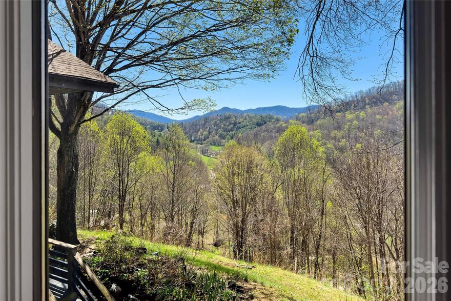 Perched at 3,117 feet in the mountains of Burnsville, this rare 15+ acre property borders 2,444 acres of protected National Forest and offers sweeping views of the Black Mountains. With pastures, springs, woodland trails, and expansive living spaces, this unique mountain retreat offers incredible potential for those seeking privacy, creativity, and room to make a home truly their own. Recently reintroduced to the market at a significant price reduction and priced below appraisal, it presents a rare opportunity in one of Western North Carolina’s most beautiful settings. PLUS IT IS PRICED WELL BELOW RECENT APPRAISAL.

Inside, the dramatic great room spans nearly 1,300 square feet beneath soaring 20-foot ceilings, creating an open living space filled with natural light. Eight skylights and expansive windows bring the outdoors in, including some  stained-glass accents. The scale of this space invites creativity—perfect for gathering with friends, creating cozy reading corners, filling the home with plants, or hosting unforgettable mountain retreats.

The spacious kitchen opens seamlessly into the great room, designed with entertaining and shared cooking in mind. Features include double ovens, gas cooktop, veggie sink, and abundant workspace, making it easy for multiple cooks to enjoy preparing meals together while staying connected to the living space and views beyond.

The main level offers a flexible layout with two spacious bedrooms, two full baths, and a half bath for guests. The primary suite is privately positioned at the end of the hall and features walk-in closets nearby with an easy opportunity to create a connected ensuite bath and closet configuration if desired.

The lower level expands the possibilities even further, offering two oversized bedrooms, a full bath, and an expansive mechanics/storage room with potential for a future kitchen or additional living area. This level could easily serve as a guest suite, multigenerational living space, or rental opportunity. A tandem two-car garage provides additional space for vehicles, workshop use, or hobby storage.

Outdoor living is equally special. Expansive decks frame breathtaking mountain sunsets, while koi ponds, springs, and blooming gardens create a peaceful mountain setting. Three open pastures provide space for animals, gardening, or small-scale homesteading—making this property a true mini-farm and pollinator’s paradise.

Recent improvements provide peace of mind and a strong foundation for the next owner, including a new elaborate plumbing system, a premium 2024 roof with storm-nailed high-definition shingles and high-flow ventilation, a new well pump with updated wiring, and a new storage building.

Recently reintroduced to the market at a significant price reduction and priced below recent appraisal, this property represents a rare opportunity to own a truly unique mountain home with incredible acreage, views, and room to make it your own.

If you’ve been searching for privacy, creative space, and a mountain setting with unlimited potential, this Burnsville retreat is ready for its next chapter.