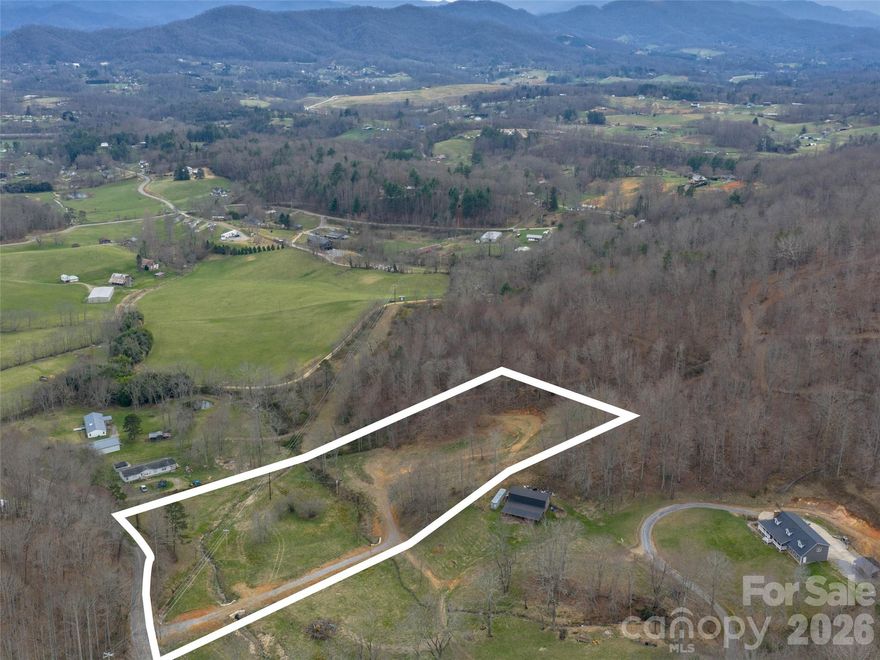 Tucked away in a serene, peaceful setting just 20 minutes from downtown Asheville, this stunning vacant lot offers the perfect canvas for your dream home or private mini-farm with tiny homes allowed. Electricity is installed and available at the site, while a gently graded gravel driveway with proper drainage provides easy access to the beautifully cleared and leveled homesite. A two-bedroom septic permit is already on file, with room to expand if desired. The lower portion of the land features flat, open pasture acreage ideal for animals or gardening, while two gentle, year-round streams flowing to the bottom boundary, adding natural charm, soothing sounds, and convenient water access—without any flood-zone concerns. The elevated homesite boasts excellent year-round mountain views, creating a tranquil backdrop for daily living. Additional features include partial fencing, a completed survey, and thoughtful grading throughout. Conveniently located just minutes from shopping, dining, and everyday conveniences, yet tucked away in a private country setting, this property delivers the rare combination of modern readiness and peaceful seclusion. With everything in place and nothing left to chance, all that’s missing is you. Come build the life you’ve always imagined in this beautiful slice of Western North Carolina.