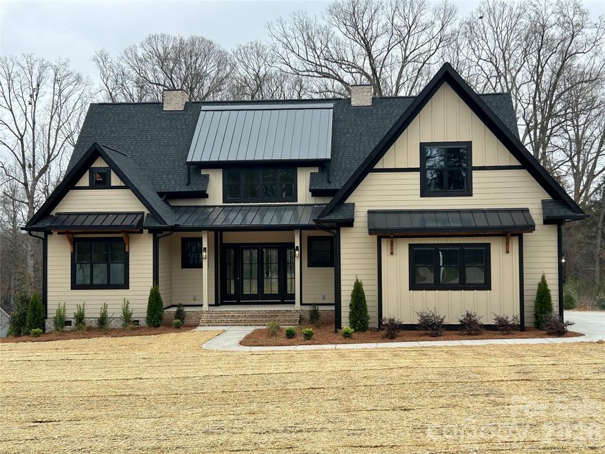 You'll be impressed upon entering this quality built, spectacular home with all the "Bells and Whistles", flooded with natural light, just minutes from Lake Norman with room for a pool! Prepare to fall in love with this stunning, well-appointed new construction home that combines modern elegance, timeless craftsmanship and the ultimate in functionality. Ideally located just minutes from Lake Norman, you’ll enjoy all the lifestyle perks of lake living, boating, fishing, waterfront dining & endless recreation, while still being conveniently close to schools, shopping, medical facilities and restaurants. This exceptional home offers the perfect balance of luxury and everyday comfort. Sitting on a level 0.69-acre lot with room for a pool, pool house or detached single car garage and no HOA, this gorgeous home with an open floor plan boasts 3,672 square feet of living space, flooded with natural light, beautiful finishes, impressive trim work, two laundry rooms, zero entry showers and primary on the main! From the moment you step inside, you’ll notice the meticulous details that set this home apart: crown molding, wainscoting, engineered hardwood floors, oak stair treads, extensive trim work, coffee/ bar with mini fridge area, nook wine shelves, built-in desks/bookcases, striking black-and-white windows & stylish tile backsplashes that give each space a distinctive touch. The chef’s kitchen is nothing short of spectacular. Designed for those who love to cook & entertain, featuring floor-to-ceiling cabinetry, 48inch natural GAS range with double oven, under cabinet lighting, oversized island with storage and a beautifully appointed scullery with a second dishwasher, microwave, tons of cabinets & ample space for everything you need. This kitchen is as functional as it is beautiful, offering plenty of prep space and seamless flow into the dining area and family room. The family room is a true showpiece, highlighted by a gorgeous fluted vertical tile fireplace wall with built-ins, floating shelves & custom mantle. A wall of windows allows natural light to flood the space while showcasing views of the backyard. With its open layout & thoughtful design, this is the perfect spot for relaxing evenings at home or gatherings with family and friends. The main floor primary suite offers a private retreat and spa-like bath complete with a zero entry shower, freestanding tub and spacious walk-in closet w/custom shelving. Also on the main level, you’ll find an office/flex room, ideal for working from home or hobbies, a laundry room with sink & cabinetry, drop zone and full bath. Upstairs you'll find 3 spacious bedrooms, 2 are connected by a thoughtfully designed Jack-and-Jill bathroom, where each bedroom enjoys its own private vanity & toilet, with a shared tiled tub/shower between. The 3rd bedroom has access to a beautiful bath with a tiled walk-in shower. A loft area with built-in desks, floating shelves & cabinetry provides an ideal space for study, TV watching or game playing, while a large bonus room offers even more flexibility for a playroom, media room or workout space and attic storage. A second laundry room adds convenience & practicality for busy households. Outdoor living is just as impressive as the interior. Step out to a covered back porch with a beautifully stained ceiling and two ceiling fans, perfect for enjoying the outdoors in comfort year-round. With nearly three-quarters of an acre, you’ll have plenty of room for outdoor activities, gardens or a future pool. The side load finished garage has been pre-wired for electric vehicle charging. Home also includes a natural gas tank-less hot water tank. Located in a highly desirable area just minutes from Lake Norman, this home offers the opportunity to enjoy the ultimate lifestyle—close to the water, in a quiet setting on a dead end street. With easy access to schools, shopping, restaurants, medical facilities & major highways, the location is as convenient as it is beautiful.