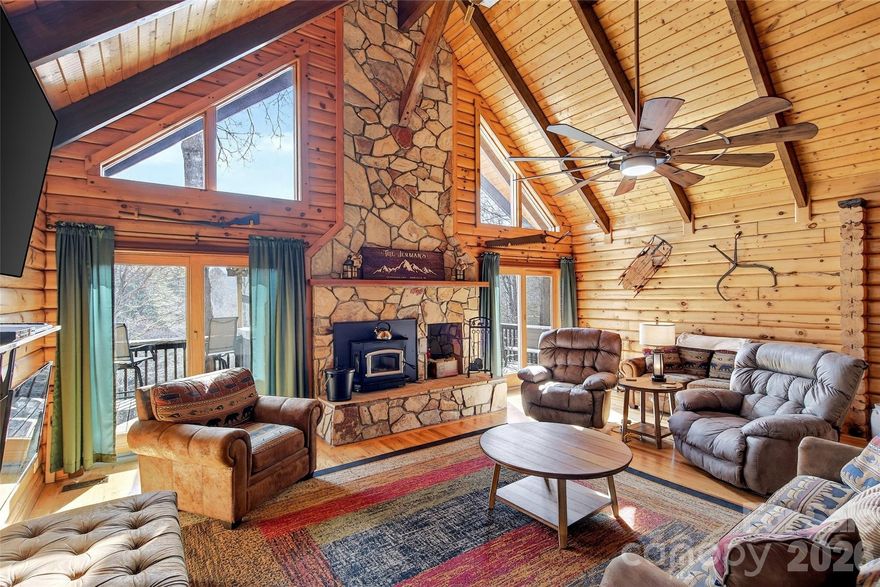 Experience the true spirit of mountain living with this stunning log cabin retreat set on 5 private acres overlooking the beautiful North Toe River. With 135 feet of river frontage, breathtaking mountain views, and a peaceful pond full of goldfish, this property offers the ultimate combination of serenity and outdoor adventure.

A private path leads down to the river, wide enough for ATVs to navigate, where you can launch inner tubes, wade in the cool mountain water, fly fish, or simply relax along the riverbank and enjoy the sound of the flowing river. This is more than a home – it’s your own private mountain adventure without ever leaving the property.

Spend your evenings soaking in the mountain views from the spacious deck, or open the windows and enjoy the cool mountain breeze while listening to the river flowing below. With Anderson windows and doors throughout, the natural beauty outside becomes part of the living experience inside.

Inside, the cabin welcomes you with a spacious open floor plan designed for gathering and entertaining. The living room features soaring vaulted ceilings and a stunning stone fireplace where a new Buck Stove was recently added, creating the perfect cozy mountain atmosphere. The dining area flows effortlessly into the kitchen featuring granite countertops, gas range, abundant cabinetry, a large island, and breakfast area.

The loft overlooks the main living area and provides the perfect space for a game room, reading nook, or additional gathering area. A pool table is in place and ready for games and laughter to begin. 

The primary suite offers vaulted ceilings, hardwood floors, a large walk-in closet, and a beautifully appointed bath with granite countertops, tile flooring, and glass shower doors. Two additional spacious bedrooms are located on the main level along with a charming guest bath featuring a classic clawfoot tub.

The attached two-car garage has been converted into two additional bonus rooms and a full bath, offering flexible space for guests, hobbies, or home office use.

Outdoor living is just as impressive with a fantastic outdoor bar on the back deck area overlooking the river, perfect for entertaining family and friends after a day of fishing, tubing, or exploring the river.

Additional features include:

• Brand new standing seam metal roof
• Whole-house generator
• Fresh mountain spring water
• Detached two-level workshop with office and half bath – ideal for woodworking or creative projects or convert it to a guest house
• Lower level of the workshop provides ample storage

From fishing in the river, riding the ATV path down to the river, floating the North Toe on inner tubes, or simply relaxing on the deck with mountain views, this property truly captures the epitome of peaceful mountain living.

This is not just a mountain home – it is a complete mountain lifestyle experience.
