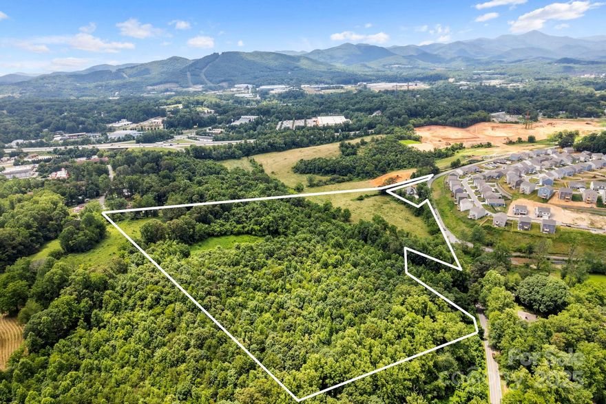This gorgeous raw land has excellent development potential.  Comprising 21 acres more or less (see attached survey) and sharing a boundary line with the new Mission Hospital site in West Asheville just off Patton Ave.  Featuring long range mountain views and a lovely creek running through it. Suitable for multifamily buildings. 12 units per acre.
Additional 12 acres available from neighboring owners MLS# 4313794 (see photos).
A portion of the property is in a floodplain.