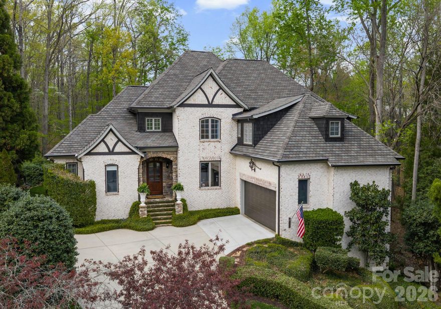 Welcome Home to your own private retreat, tucked into a serene wooded cul-de-sac setting just minutes from the conveniences of Matthews and Charlotte. This custom all-brick residence offers six bedrooms and exceptional living space designed for both everyday comfort and effortless entertaining. Set on a premium lot with abundant open space for recreation, the home blends timeless architecture with a peaceful natural backdrop.
Inside, dramatic design elements make an immediate impression, including a 30-foot cedar-paneled ceiling, a dramatic tapered river stone fireplace with solid timber mantel, and a stunning two-story wall of windows that bring the outdoors into the heart of the home. 
In 2026, the main level was enhanced with curated designer lighting, while the chef’s kitchen was beautifully remodeled with an expansive island and handmade Moroccan Zellige tile.  The kitchen flows seamlessly into the breakfast area, keeping room and screened in porch, creating an inviting space for gathering. Main floor living areas with 10' ceilings connect beautifully for entertaining while offering elevated views of the expansive backyard. The main-level primary suite provides convenience and privacy, while the second floor features three spacious bedrooms, each with its own ensuite bath and a bonus room. 
The ground floor is unmatched with 10’ ceilings and includes media and entertainment area with speakers, dedicated fitness space, kitchenette, office/bedroom, guest bedroom/bath, plus an additional flex room ideal for a den, wine room, or music room. The ground level also functions perfectly as a guest suite or private living quarters for a nanny or extended stay visitors.
Additional features include: extensive hardwood flooring, Italian porcelain tile, solid-core doors, and upgraded millwork reflecting the quality found throughout. Two laundry rooms, three fireplaces, built in speakers and generous walk in storage add comfort and function throughout the home.
Conveniently located to private and public schools, restaurants, retail, shopping and Uptown Charlotte.
Homes like this are rare, with its peaceful setting and expansive layout, this home truly feels like a vacation every day.