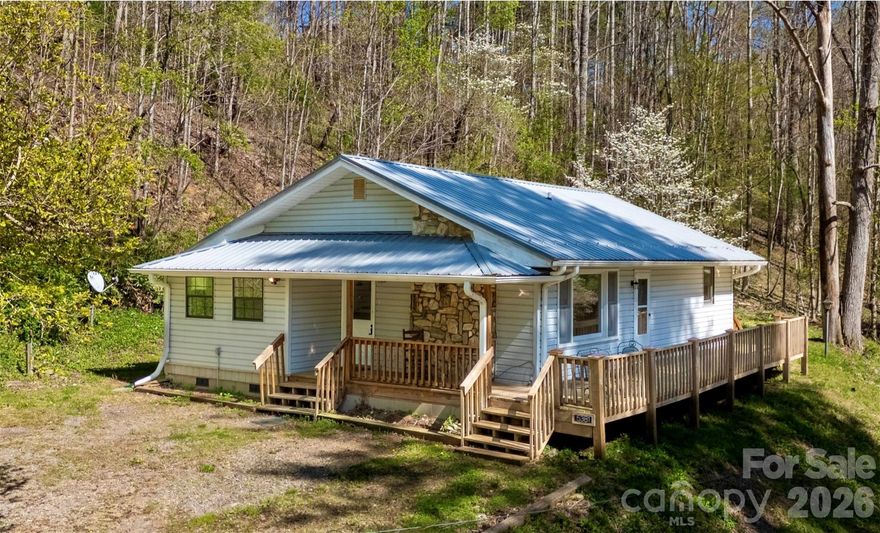 Another Price Drop – Now $3,000 Lower! This Treasure Just Got Even More Irresistible! Stunning, Unaffected River-View Retreat – Your Proven Safe Haven Awaits! Proudly Resilient & Completely Unaffected by Hurricane Helene. When Helene brought historic flooding to parts of the Cane River valley in September 2024, this home stood strong—high and dry with zero damage. Its smart elevation and solid build made it one of the true success stories along the river, untouched while the community has since fully rebounded: roads, bridges and river access restored, infrastructure repaired and the serene mountain lifestyle thriving once again.  Nestled serenely along the pristine Cane River, this captivating 2-bedroom, 2.5-bath gem with a versatile bonus/flex room perfectly blends modern comfort and breathtaking mountain tranquility. Inside, an open-concept living space bathes in natural light, featuring gleaming oak hardwood floors and a dramatic floor-to-ceiling natural stone fireplace as the cozy centerpiece. The chef-inspired kitchen flows seamlessly into the dining and living areas—ideal for lively gatherings, family meals or quiet evenings by the fire.  Step outside to a covered side porch and spacious open front deck, where you can unwind with stunning river and mountain views. Just moments away from the Cane River that invites you to dip your toes in the cool, clear waters —perfect for fishing, tubing or simply soaking in nature's beauty. Equipped with a durable metal roof, central HVAC and recent upgrades throughout, this Move-In-Ready retreat is truly turnkey—no surprises, just peace of mind.  Why wait or rent when you can own this peaceful paradise at an unbeatable price—now even more affordable after our latest $3,000 reduction? Imagine sipping your morning coffee on the porch, watching the gentle flow of the river and embracing the mountain life you've always dreamed of... in a home that's already proven it can weather the storm.  Prime location: Just 5 scenic miles to charming downtown Burnsville's cafes, art galleries and local shops; only 45 minutes to vibrant Asheville for culture, dining and amenities.  This rare survivor won't last long—act now and claim your riverside retreat in one of Western NC's most beautiful, recovering gems!