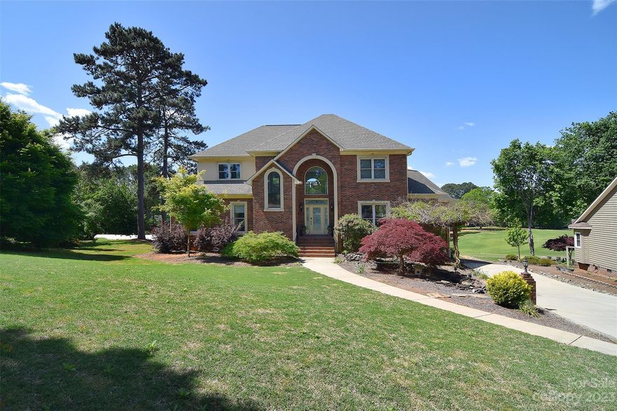 Admire your well landscaped lawn & pull into your 2 car, side load garage. Guests have a side walk to covered 2 story entrance. Foyer greets you w/tile floor & open floor-plan. Living room opens to 2nd floor walkway & is adorned w/semi floor-to-ceiling windows & fireplace. Dining room offers natural light & art display niche. Kitchen is equipped w/ double wall oven, gas stove, SS appliances, & lots of cabinets. Den is adorned w/windows & overlooks golf course. Primary on main w/raised lounge area. En-suite is stellar w/soaking tub, oversized shower & dual vanities. 2nd floor has split layout & three additional BRs & 2 full baths. Basement is finished w/BR & access to back yard at covered patio. Main floor offers large patio w/views of 16th hole. Home also offers laundry chute, central vac w/baseboard suction trash removal, 9ft ceilings, 6 to 8ft windows, & so much MORE! Membership to Cowans Ford is optional: Amenities are clubhouse, pool, golf, tennis, boat launch & walking trails.