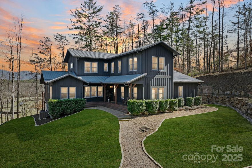 Stunning modern custom farmhouse built in 2017, featuring 4 BR, 3.5 BA, beautifully set on a serene, wooded 2.25-acre lot in highly desirable East Asheville. Enjoy captivating panoramic mountain views overlooking Bull Creek from nearly every room. Open-concept main level ideal for entertaining or relaxed evenings at home, highlighted by hardwood floors and built-in Sonos sound system. The kitchen includes built-in cabinetry, farmhouse sink, oversized walk-in pantry & cozy dining nook perfect for casual meals or a quiet study area. Versatile flex room on main level suitable for office or guest use. Spacious sundeck showcases breathtaking sunset mountain vistas; expansive Nolichucky river rock firepit area w/ impressive boulder retaining walls ideal for gatherings. Main-level in-law suite w/ full kitchen, living area & private entrance. Bright, airy primary suite upstairs w/ vaulted ceilings, dual vanities, walk-in shower & custom closet. Ample parking including potential RV space.