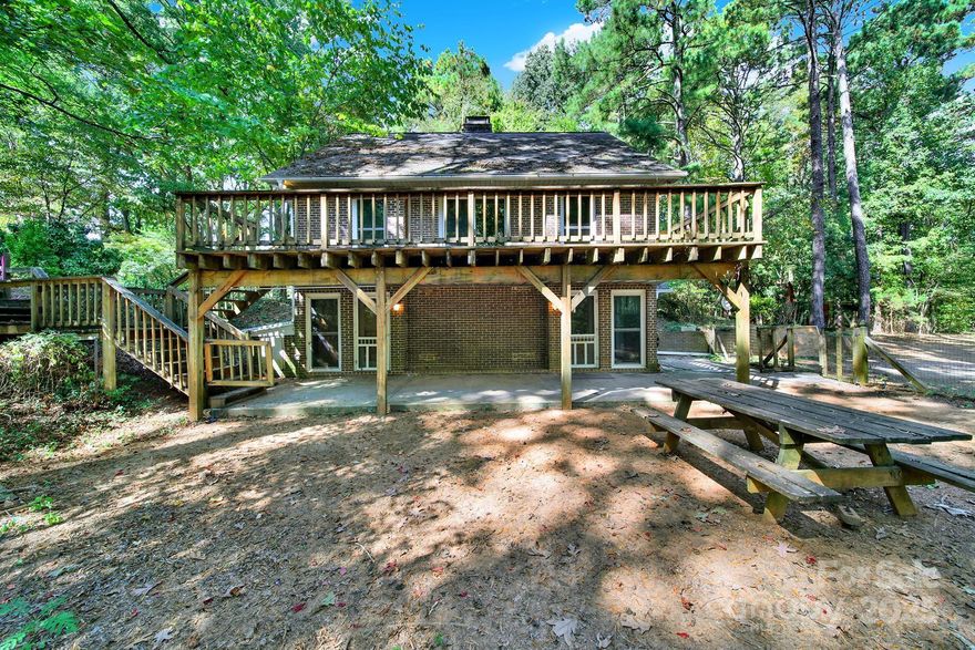 Here’s your shot at something rare. 12+ acres and a full-brick custom home that doesn’t just blend into the crowd. Built with passive-solar design in mind, this 2.5-story home has the soul of a rustic cabin. The driveway winds through the trees, delivering you to a massive deck overlooking the beautiful woods. Step inside to a living room with natural wood beams and a wood-burning fireplace, then swing around to a kitchen with a large island, dining area, and walk-in pantry/laundry room. Head upstairs and you’ll find another living space with a shiplap vaulted ceiling and windows galore that make the outdoors part of the décor. Two bedrooms share a bath on this level, and another set of stairs takes you up to the loft with two more bedrooms and a full bath.
Outside, the land is full of wildlife and is perfect for trails, play, or just breathing room. Three sheds are already in place, and according to Lancaster County, the property can be subdivided up to five times (though each new parcel would need a direct driveway). All this sits right off booming Highway 521 between Lancaster and Indian Land, just two miles from Andrew Jackson State Park and a stone’s throw from the NC line.
If you’ve been waiting for a property full of potential, character, and room to grow, this is it.