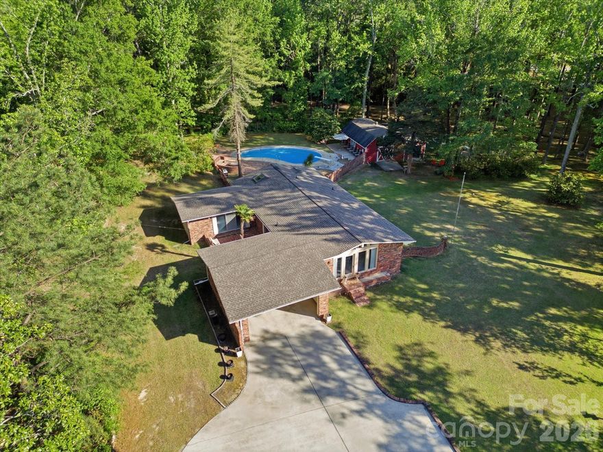 This bright, open ranch home sits on a lush 2.28-acre lot and offers a seamless indoor-outdoor flow with a light-filled floorplan. The backyard is a private oasis with a gunite pool, brick patio, and deck. Mature trees, creek bridges, and tree swings throughout the property create a storybook setting perfect for exploring or relaxing. The wired barn makes an ideal shop or recreational space.  Inside the home, a spacious family room connects to a sunny kitchen that is open to the dining room, where sliding doors lead to a charming courtyard. The dining room flows into a sunroom with direct access to the backyard. The home has a convenient split bedroom plan, with three bedrooms and two full baths. With only 2 owners since 1966, this home has been lovingly maintained and is a beautiful canvas for your personal vision.