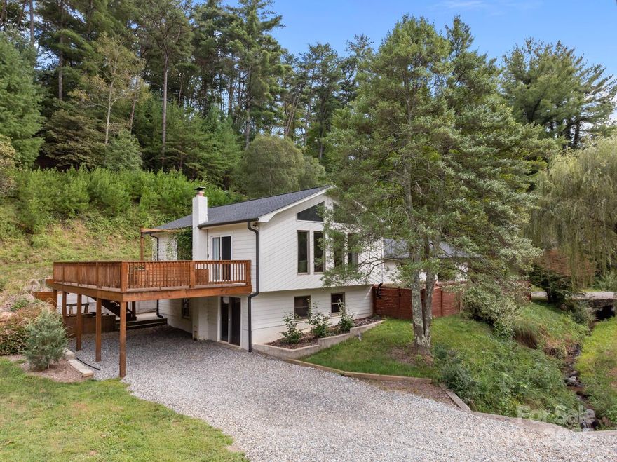 Discover peace, privacy, and mountain views in this updated split-level home. Filled with natural light, the spacious interior features touches of mid-century styling that add unique character. The expansive kitchen with island is ideal for cooking or entertaining, while the large deck—accessible from both the living room and primary suite—offers the perfect spot to take in the views. Vaulted ceilings in the living room and primary bedroom create an airy, open feel, complemented by dual walk-in closets with built-ins. The primary bath is generously sized for the era, with dual vanities, a separate tub and shower, plus a private toilet area. The lower level provides excellent space for projects, storage, or hobbies, with convenient outdoor access that bypasses the main living area. Outdoors, you’ll find a fenced dog run, ample parking on both sides of the home, and newer systems including HVAC and an on-demand water heater. A short walk up the hill leads to a shed and screened porch, complete with a fire pit for cozy evenings under the stars.