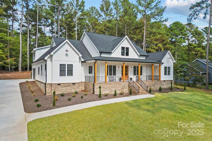 This recently built modern farmhouse (2024) still looks brand new and is filled with fantastic upgrades! Quartz countertops throughout from the large breakfast bar island to each bath and the laundry room. The kitchen features a walk-in pantry, white cabinets with hidden trash-pullout and soft-close drawers, subway tile backsplash, a Wolf smooth-top induction cooktop, and stainless kitchen appliances including a Sub-Zero refrigerator, Bosch dishwasher, Wolf built-in microwave, Wolf wall-oven, and a warming drawer. It is open to the dining room and great room, which features a vaulted ceiling and an electric fireplace with floor-to-ceiling shiplap surround. There is an office off the great room with barn doors that can be shut for privacy. The primary suite on the main level is a wonderful retreat with vaulted ceiling, large walk-in closet with closet system, and a stunning bath with a beautifully tiled shower, freestanding tub, 2 sink/vanity areas with smart mirrors, and a separate water closet. On the other side of the home, you'll find 3 more bedrooms and 2 more baths (also beautifully upgraded), and a barn door can be used to close off one of the full baths along with 2 of the bedrooms if you'd like to create a private area for in-laws or guests. A spacious laundry room with sink and a powder room round off the main level. Upstairs you'll find a huge bonus room and a partially floored walk-in attic for storage. The oversized 2-car garage includes a Tesla charger. You'll love relaxing on the huge covered rocking-chair front porch with wood columns and black metal railings, and on the covered porch in the back overlooking the wooded portion of the lot for ultimate privacy. This home is just steps away from community trails that go around the lake. Anchors Landing surrounds Emerald Lake, Heron Lake, and touches Lake Hickory as well. It is a gated community, so you are allowed to use a golf cart to visit the amenities, which also include a clubhouse and pool. Come live the good life in Anchors Landing in this gorgeous like-new home!