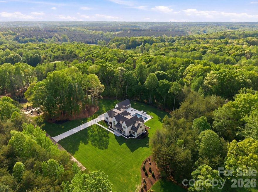 Discover an extraordinary level of elegance in this newly built, custom-crafted estate, perfectly positioned on 3.48 secluded acres in the heart of Davidson. Every element of this 5-bedroom, 6.5-bath masterpiece with 4-car garage exudes refined sophistication and timeless artistry, showcasing unparalleled high-end finishes and meticulous craftsmanship throughout. A grand two-story foyer introduces the home’s architectural symmetry and soaring staircase, setting a dramatic tone that continues into every space.

Designed for elevated living and effortless entertaining, the residence unveils resort-style amenities including a shimmering in-ground pool, integrated hot tub, fire features, expansive terrace, and a fully appointed pool house with full bathroom—all harmonizing to create a private outdoor oasis. Multiple outdoor kitchen areas, a covered rear porch with fireplace, retractable screens, and grand stairs descending to the terrace seamlessly blend indoor comfort with alfresco luxury.

The gourmet chef’s kitchen stands as the heart of the home, boasting bespoke custom cabinetry, a generous entertainment island with farmhouse sink, stainless steel appliances including gas range and beverage cooler, plus a professional-grade butler’s pantry with secondary refrigerator, sink, and extensive storage. Thoughtful utility spaces include a refined mudroom with built-ins, sink, laundry, and coat closet.

The main-level primary suite epitomizes luxury with intricate millwork, a spa-caliber bathroom featuring an oversized shower, freestanding soaking tub, stackable laundry area, and an expansive boutique-style custom closet. A secondary bedroom, ideally suited for a home office or guest suite, completes the main level with an additional full bathroom.

The second floor reveals three beautifully appointed ensuite bedrooms with custom closets, an elegant bonus room with a hidden finished storage room, half bathroom, and dedicated laundry room with sink and storage galore. No element has been overlooked—every detail, from designer lighting to curated finishes, has been thoughtfully selected to create a home that is as functional as it is breathtaking.

A fully sodded lawn and lush, professionally designed landscape complete the estate’s 3.48-acre setting, offering supreme privacy yet effortless access to Davidson’s finest conveniences. Outdoor enthusiasts will appreciate proximity to River Run Country Club, Fisher Farm Park & Davidson Greenway, and nearby shopping and dining. Not to mention being less than a mile from Summit Farms!

A true sanctuary, this estate defines Davidson’s pinnacle of luxury—where privacy, sophistication, and craftsmanship converge in perfect harmony.