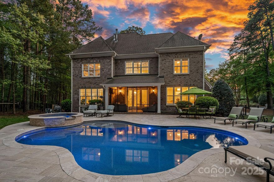 An exceptional kitchen anchors the heart of this home, showcasing leathered quartzite countertops & full-height backsplash, a striking waterfall-edge island, & custom inset cabinetry that stretches from floor to ceiling. Thoughtful touches include appliance garages, pull-out drawers, & a Wolf Induction Cook Top. The open floor plan seamlessly connects the kitchen to a stunning great room, where a gas fireplace is accented with stylish tilework, elegant wainscoting, white oak shelving, and on-trend sconces.
Outdoors, the gunite pebble tec heated saltwater pool & spa—constructed in 2021—stands as a true showpiece, even featured in the builder’s advertising portfolio.
This stunning brick home is designed with every detail today’s discerning buyer desires: a boat slip w/ lift, a three-car garage, screened-in porch, expansive Travertine patio, fire pit, a home office w/ coffered ceiling, a billiard room, a generous bonus room, three large guest bedrooms and a main-level owner’s suite.