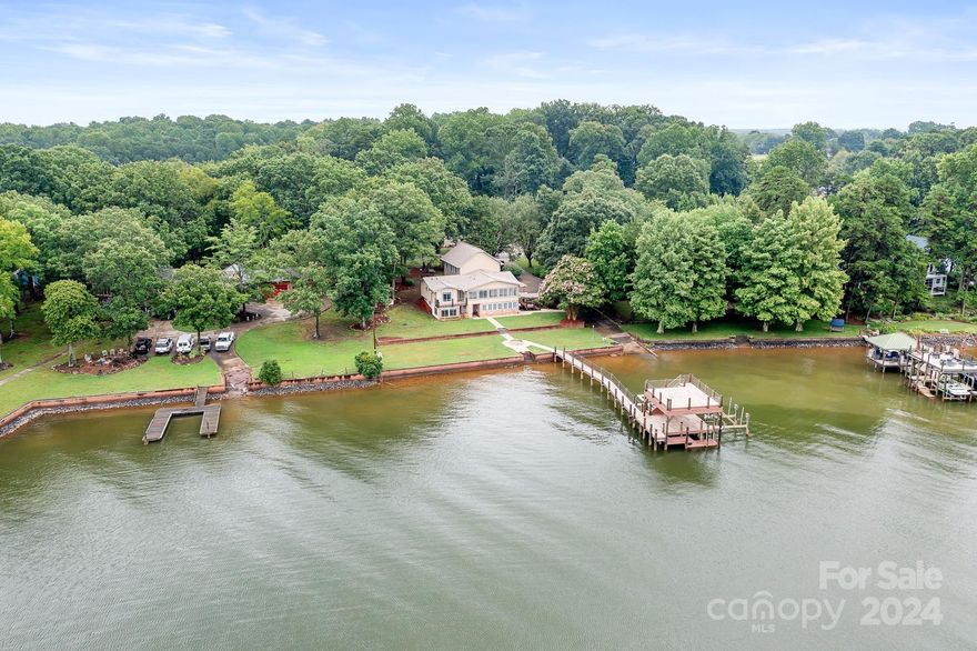 Lakeside living awaits at this unique LKN property! Take in gorgeous, west-facing sunset views from inside this split level retreat or enjoy them from the impressive 2 level Italian tile dock, complete w/lighting, lifts for your boat & watercrafts, & ample storage. You'll also have the added convenience of your own private boat ramp. Renovations/updates over the years have enhanced the convenience & functionality of the home but the original charm & character of a lakeside cabin remains. The main level living area features exposed beams & a fireplace w/ lake views via the sunroom, while the primary bedroom features a balcony overlooking the lake. The updated kitchen includes quartz counters, stainless appliances & modern cabinetry. The daylight basement offers additional living space boasting a great room w/fireplace, a bedroom w/lake view, a kitchenette, & workspace. Finished space over the garage is an HD enthusiast's dream complete w/a full bath & tiled walk in shower!