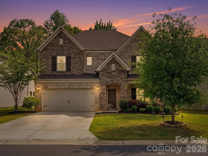 A truly stunning five-bedroom, three-bath residence in Fort Mill, showcasing timeless stone and brick accents and a gracious covered front porch that warmly welcomes you home. Step inside the two-story foyer that opens to a spacious formal dining room with tray ceiling—perfect for gathering and hosting. The kitchen is both stylish and functional, featuring lovely white cabinetry and tiled backsplash, wall oven, gas cooktop with vented hood, a large island with bar seating, a breakfast area, and both a butler’s pantry and walk-in pantry. It flows seamlessly into the light and bright family room boasting a gas fireplace, creating a warm, comfortable space where everyone can come together. Enjoy the fenced backyard that backs to woods, offering added privacy and a peaceful setting to relax or unwind. The main floor also includes a guest bedroom, along with a convenient drop zone/mud area and full bath for everyday ease. Upstairs, you’ll find an expansive loft/media room, three additional bedrooms, a full bath, and a spacious laundry room. The primary suite is a true retreat, complete with a tray ceiling and an en suite bath with a double-sink vanity, soaking tub, separate shower, private water closet, and a large walk-in closet. Neutral paint and flooring throughout enhance the home’s warm feel. Welcome home!