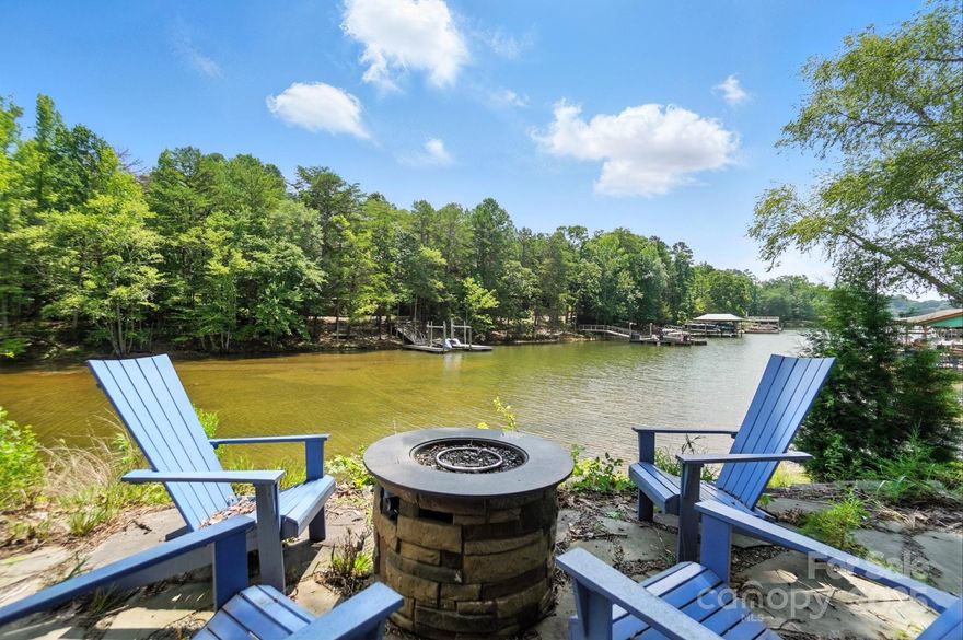 Discover the tranquility of lakeside living nestled in a quiet cove! Large windows & thoughtfully positioned rooms ensure that the scenic views are a constant backdrop. Inside, you'll find beautiful hardwoods, a great room filled w/ natural light & an open layout ideal for entertaining. The main-level primary suite is a true retreat w/ access to the back porch where you can enjoy peaceful mornings overlooking the water.  Spacious additional bedrooms & 2nd great room in the basement along w/ a flex space ideal for conversion into a gym or studio.  A key feature of this home is the outdoor oasis w/ the integrated hot tub that offers year-round enjoyment. The highlight of this property is undoubtedly the direct access to the lake. A set of stairs leads down to the water's edge, providing a seamless transition for swimming, paddle boarding or kayaking. Whether you're looking for a weekend getaway or a full-time lakefront sanctuary, this home offers unmatched privacy, views & lifestyle!