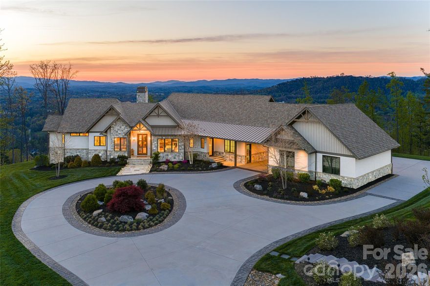 On expansive, usable acreage overlooking Weaverville's desired Reems Creek Valley, 154 Bear View presents an exceptional estate where elevated design, remarkable craftsmanship and sweeping long-range views converge. A circular driveway winds through thoughtfully curated natural landscaping, where stone elements are artfully integrated, creating a striking and private approach. Inside, the residence showcases a level of fit and finish that defines luxury mountain living. A dramatic entry with herringbone-patterned hardwood floors introduces the home, flanked by a richly appointed office with custom built-ins and a formal dining room with tailored millwork. The great room unfolds with vaulted ceilings, exposed wood beams and antler chandeliers, anchored by a statement fireplace with integrated cabinetry. Framed by soaring timber beams, the covered rear porch is a seamless extension of the home’s design, offering scale and comfort. Automated screens create an indoor-outdoor experience while preserving the sweeping mountain views, and a stone fireplace anchors the space for year-round enjoyment. Just beyond, an open-air grilling deck adds function and flow, ideal for effortless entertaining in an elevated setting. The kitchen is a showpiece and a working culinary space, anchored by an oversized island with quartz surfaces and custom beam detailing. A curated suite of Hestan appliances includes a commercial-grade range with griddle and dual ovens, wall oven, warming drawer, microwave and dishwasher, complemented by a built-in Miele espresso system. The walk-in scullery elevates functionality with extensive built-ins, a prep sink, quartz counters and a dedicated wine tower, while the adjacent breakfast nook captures soft morning light and views of the surrounding landscape. Privately positioned, the primary suite offers a retreat with vaulted ceilings, wood beam accents, a fireplace and direct access to a private deck overlooking the mountains. The spa-inspired en-suite bath features herringbone tile flooring, a freestanding soaking tub, dual vanities with under-cabinet lighting and quartz countertops, and an oversized walk-in shower with dual heads and integrated seating. Barnwood accents, curated lighting, and a custom walk-in closet complete the experience with warmth and refinement. Two additional guest suites on the main level provide comfort and privacy, each with en-suite baths, while the lower level continues the home’s sense of scale and versatility. A light-filled stairwell with a full wall of glass leads to a spacious family room with coffered ceilings and built-in media cabinetry, opening to a lower patio for additional outdoor living. A fully equipped bar and secondary kitchen, complete with beer tap, full-size refrigeration and microwave, create an ideal setting for entertaining or multi-generational living. Additional guest suites with private patio access and well-appointed baths offer flexibility and function. Engineered white oak flooring, extensive custom millwork, layered textures, and curated materials throughout underscore the home’s commitment to quality and timeless design. The surrounding acreage offers gentle topography and exceptional usability, while the elevated setting ensures uninterrupted views and a sense of privacy. Designed for everyday living and elevated entertaining, the property includes an attached one-car garage with a breezeway connection to a two-car garage outfitted as a private gym and the added assurance of a whole-home generator. Ideally just minutes from the charm of downtown Weaverville and a short drive to the vibrant dining, arts and cultural scene of Asheville, the property also offers convenient access to the scenic beauty of the Blue Ridge Parkway and outdoor recreation of Pisgah National Forest.