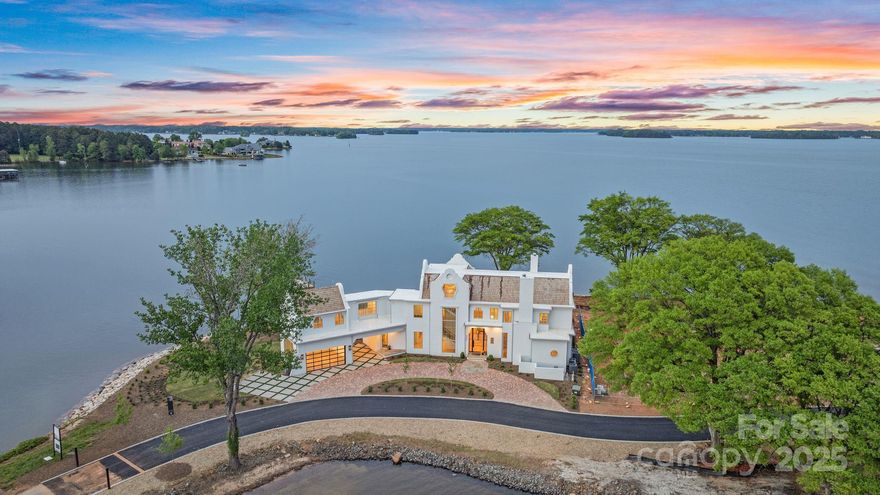 Experience luxury lakefront living at The Cape at Mattie Rose, an awe-inspiring private island enclave on Lake Norman, crafted by Grandfather Homes and Greg Perry Design. The Skyros estate offers a rare fusion of Mediterranean elegance and modern design, featuring a stucco exterior, soaring ceilings, and floor-to-ceiling windows framing 360-degree water views. This architectural masterpiece includes two distinct primary suites, smart home technology, energy-efficient systems, and a private dock. Accessible by a meandering causeway, the gated community boasts only three expansive homesites, each over 0.7 acres, with immediate lake access and boundless outdoor living. Designed to delight the eyes and refresh the soul, this home offers a retreat for mind, body, and spirit—where every day feels like a vacation and luxury meets serenity.