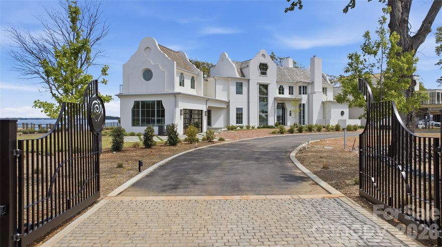 Experience luxury lakefront living at The Cape at Mattie Rose, an awe-inspiring private island enclave on Lake Norman, crafted by Grandfather Homes and Greg Perry Design. The Skyros estate offers a rare fusion of Mediterranean elegance and modern design, featuring a stucco exterior, soaring ceilings, and floor-to-ceiling windows framing 360-degree water views. This architectural masterpiece includes two distinct primary suites, smart home technology, energy-efficient systems, and a private dock. Accessible by a meandering causeway, the gated community boasts only three expansive homesites, each over 0.7 acres, with immediate lake access and boundless outdoor living. Designed to delight the eyes and refresh the soul, this home offers a retreat for mind, body, and spirit—where every day feels like a vacation and luxury meets serenity.